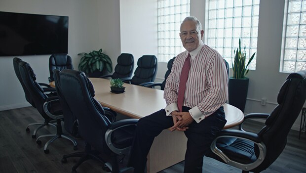 Man in business attire sits on the edge of a conference room table.