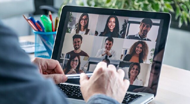 Closeup of hands working on laptop screen, with a video conference in progress.