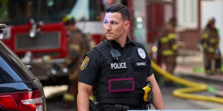 An alert police officer in uniform stands ready at the scene of an emergency.