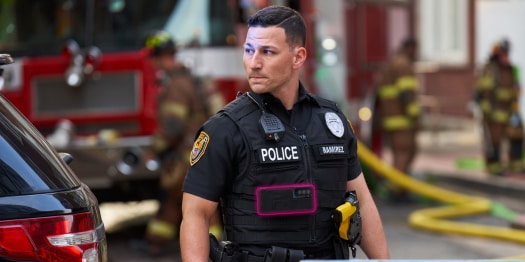 An alert police officer in uniform stands ready at the scene of an emergency.