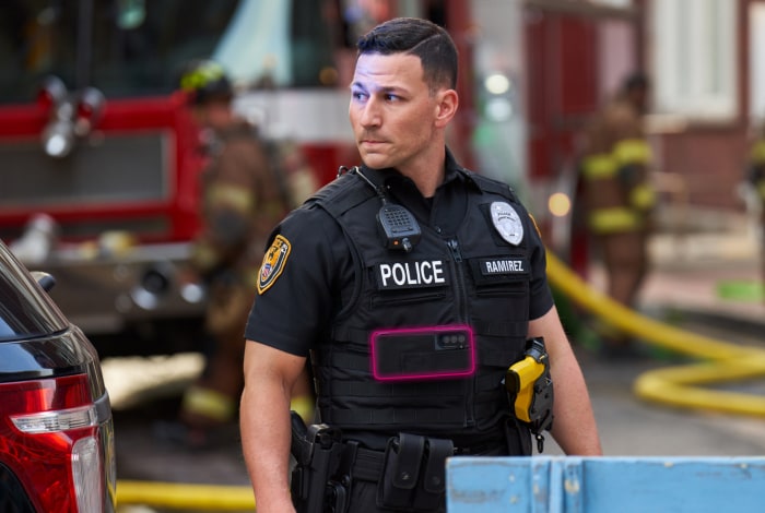 An alert police officer in uniform stands ready at the scene of an emergency.