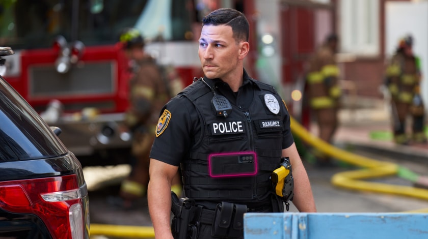 An alert police officer in uniform stands ready at the scene of an emergency.