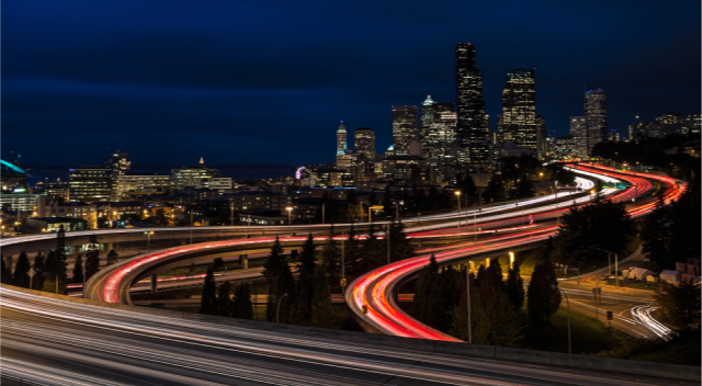 Glowing highways lead into a city at night.