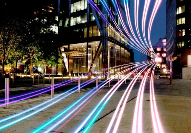 View of a city sidewalk with colorful line illustrating 5G network.