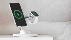 A wireless charger on a nightstand, charging a smartphone and smartwatch.