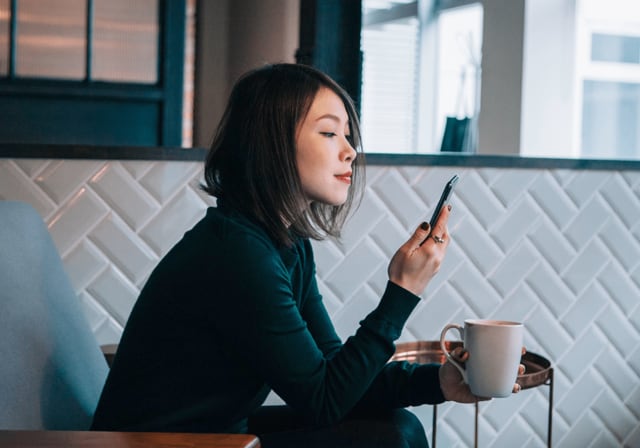A person sitting in a chair looking at their iPhone