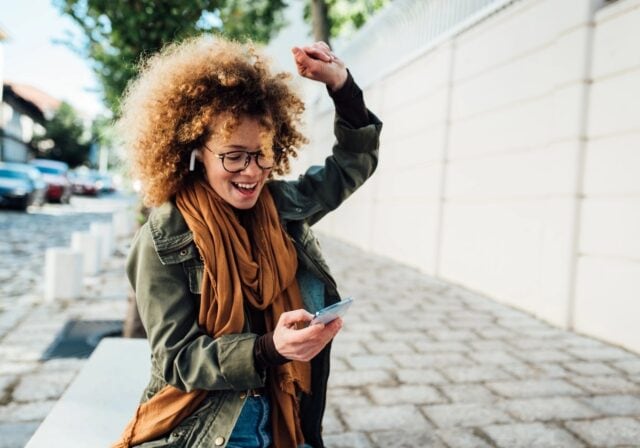 Girl listening to music with headphones in, dancing in the street.