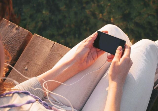 A person holding an iPhone while sitting down.