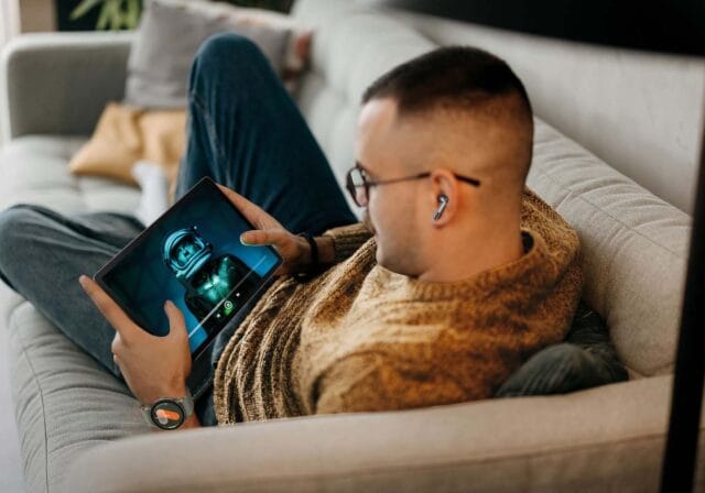 A man sitting on a couch watching a video on a tablet.