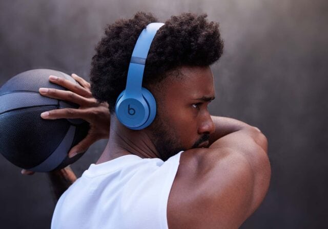 A person holding a basketball while wearing over-the-ear headphones.