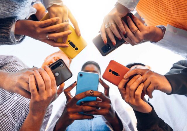 Teens in a circle holding their cellphones.