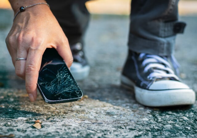 person-picking-up-smartphone-broken-screen