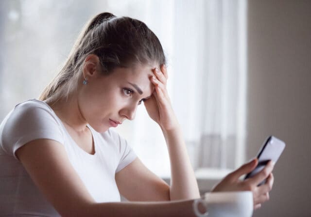 Angry-young-woman-looking-at-phone