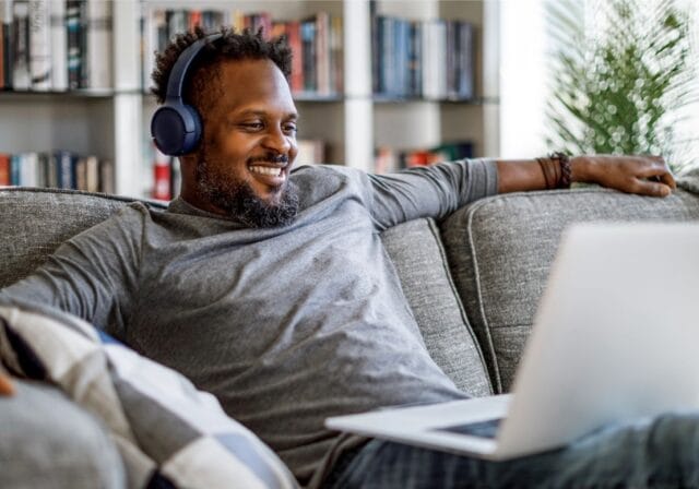 A person with headphones on watching their laptop using WIFI