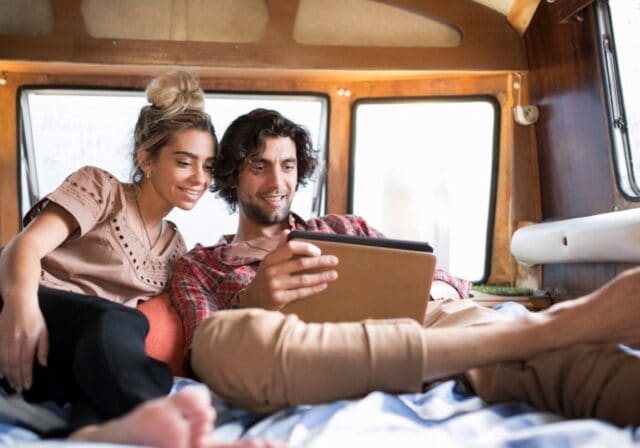 Man and women sitting together in the back of an RV camper while looking at a an iPad.