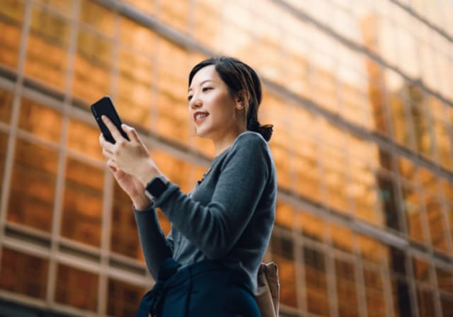 A person looking at their phone in front of a building.