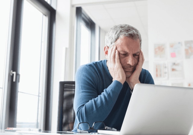 A frustrated person looking at their laptop.