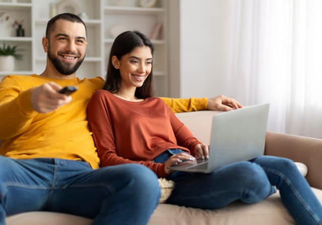Two people smiling while sitting on their couch.