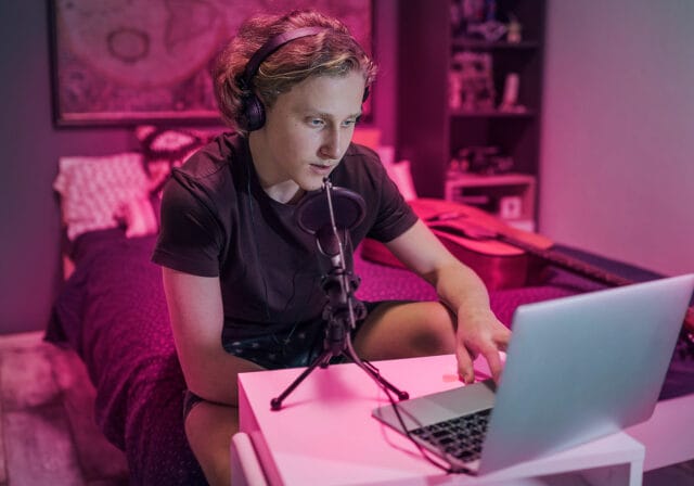 A person using a laptop and a microphone to stream from home.