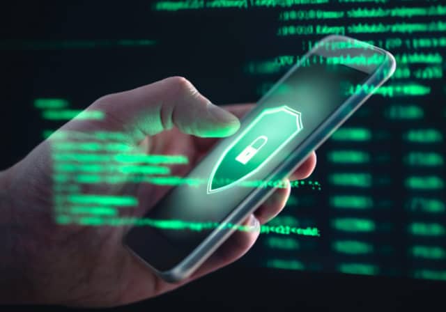 An image of a person using a phone with a green shield on the screen, signifying internet security.