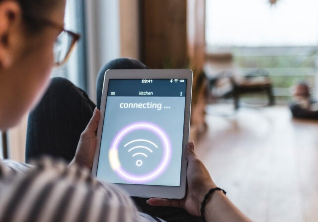 A person holding a tablet that shows messaging on screen of attempting to connect to the internet.