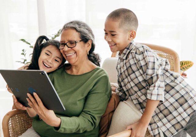Grandmother And Grandsons Playing With Tablet