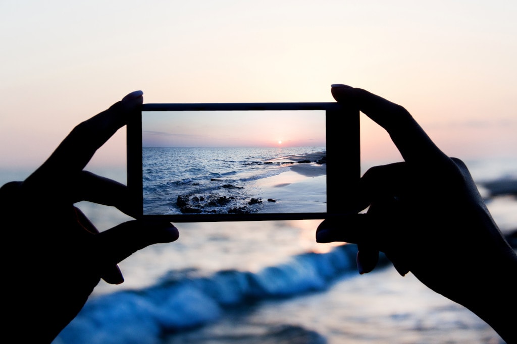 girl taking sunset photo with phone camera