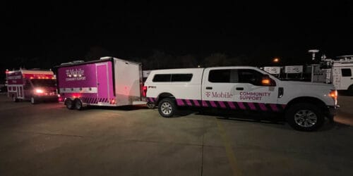Two T-Mobile branded emergency response trucks in an open parking lot during the night time