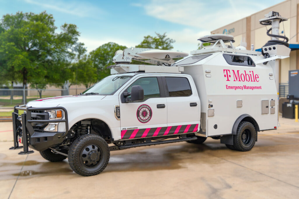 Camioneta con el logotipo de T-Mobile lleva el nombre de Manejo de emergencias. El equipo satelital del vehículo está replegado para mostrar su portabilidad y está estacionado al aire libre