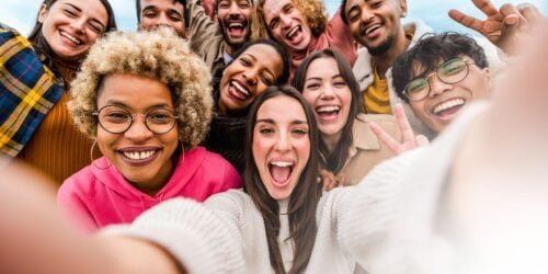 A group of people taking a selfie in front of a camera with blue sky background