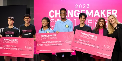 Six students standing on stage holding three large checks for T-Mobile's Changemaker Challenge Lab.