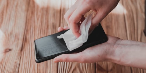 Person wiping the screen of a smartphone