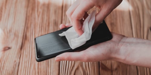 Person wiping the screen of a smartphone