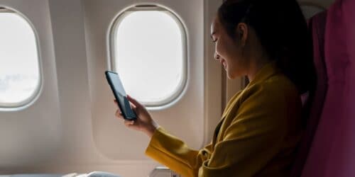 woman sitting on plane looking at phone