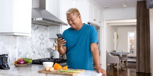Person looking at their phone while in front of a table with vegetables