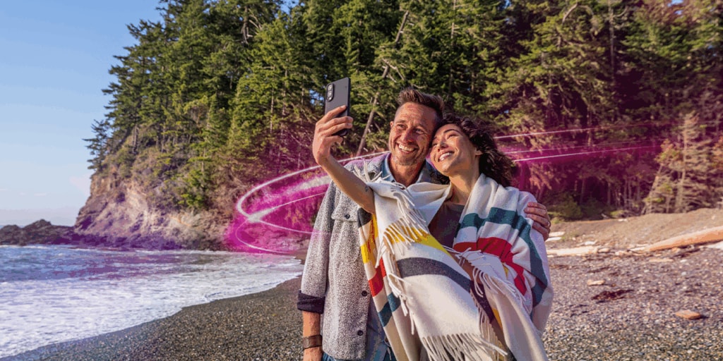 A couple looks at their phone on a beach