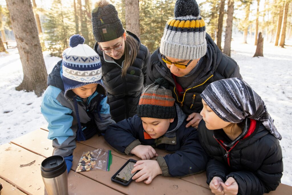 Family looking at phone in snowy woods